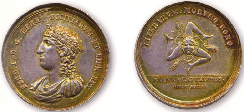 Figura 9: 1823 per il merito nelle scienze e nella istruzione in Sicilia (D’Auria 141); D./ FERD. I. D. G. REGNI SICILIARVM ET HIER. REX. ; Busto coronato e corazzato a sinistra con lunga chioma. Sotto: FF. COSTANZA INC. R./ LITERARVM . MORVMQ . BONO . ; Trinacria con spighe di grano. In esergo: SVPREMI . CVRATORES = MDCCCXXIII.